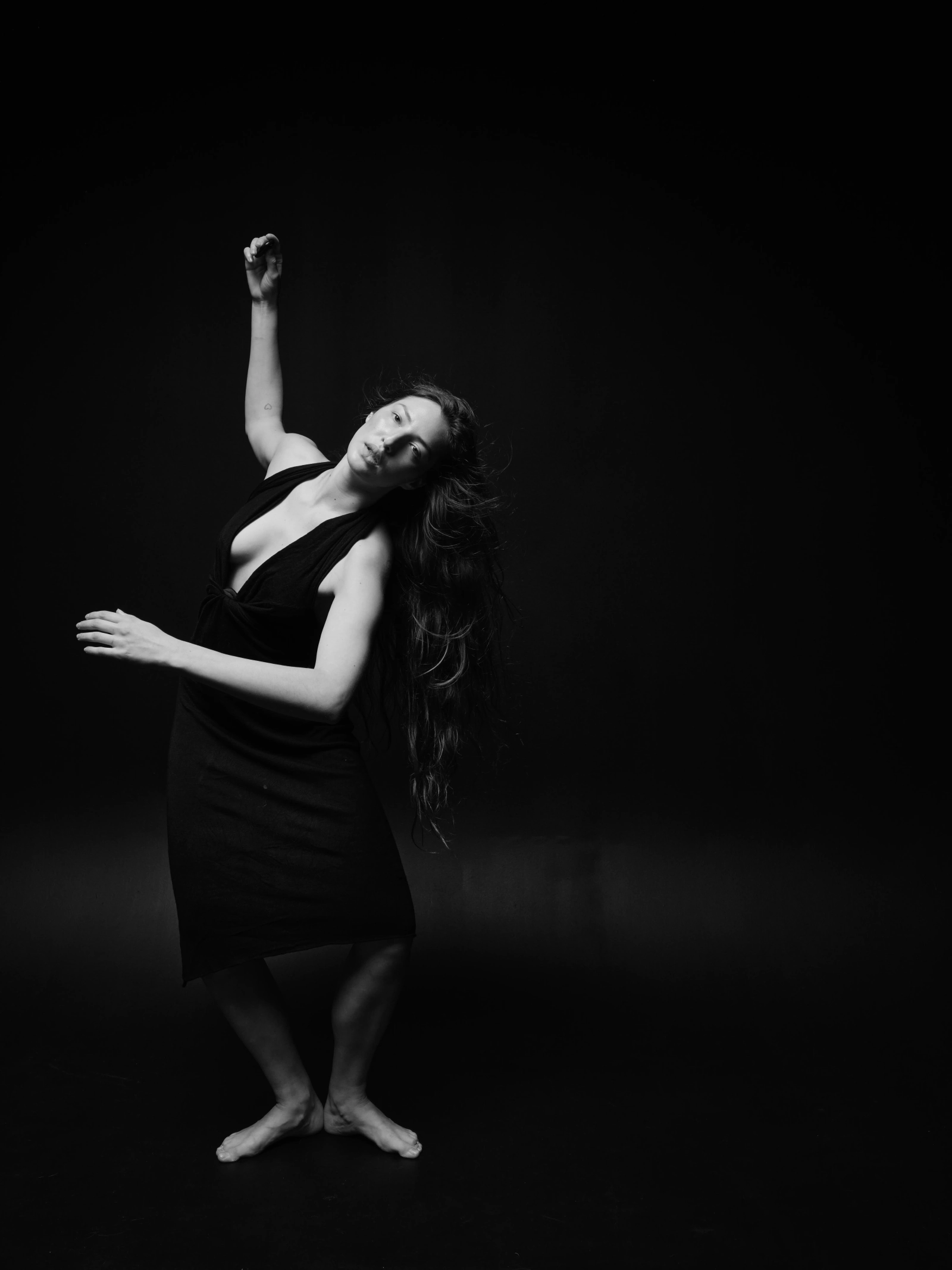 a woman dancing in a black dress, black background