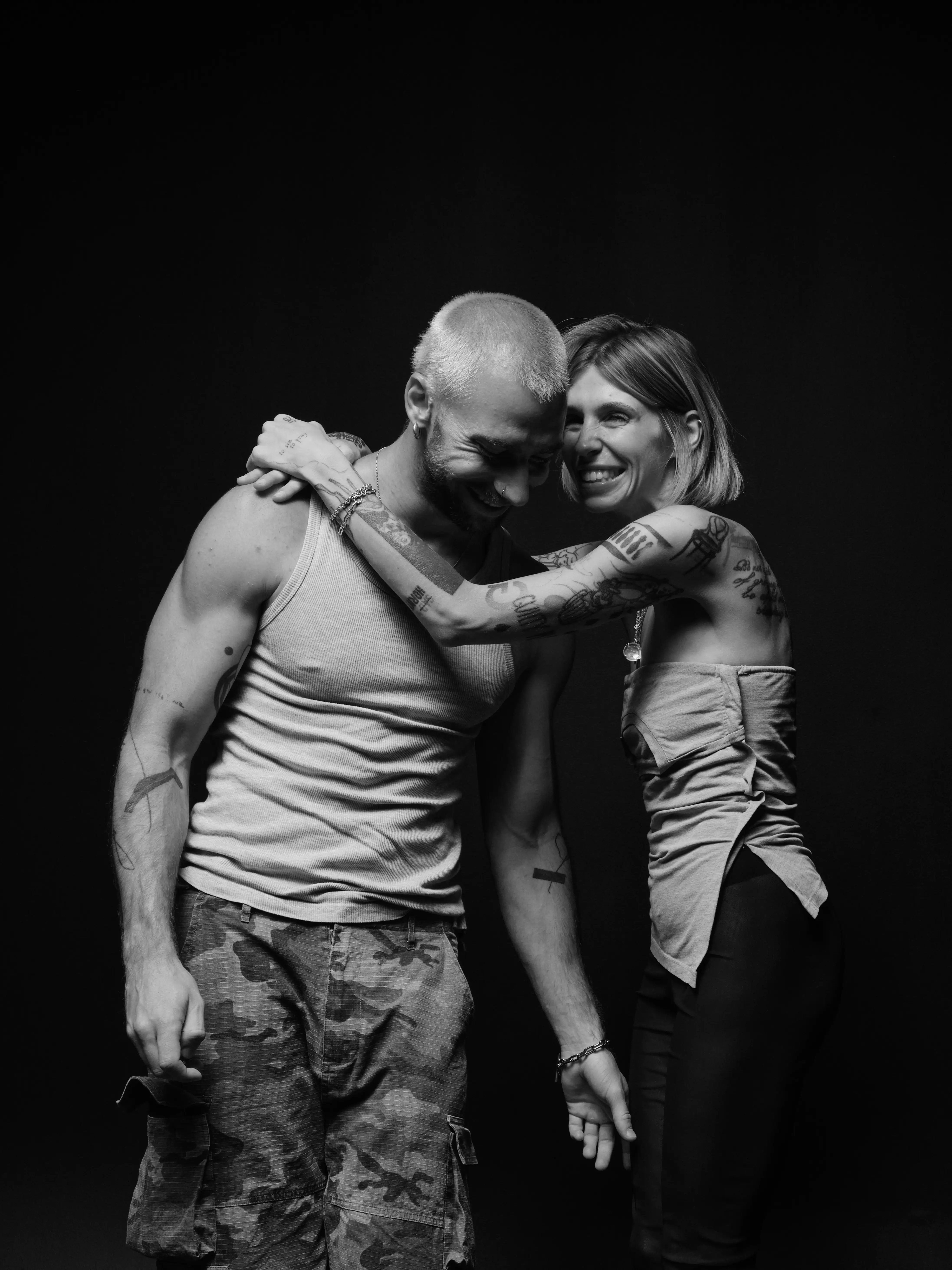 a couple laughing and hugging, black background