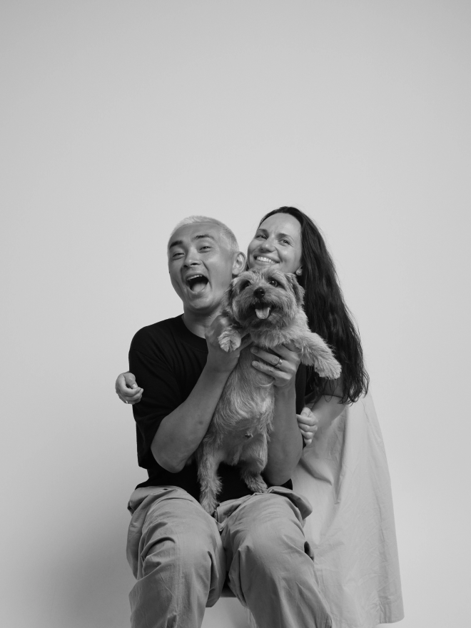 a couple laughing with their small scruffy dog, white backdrop